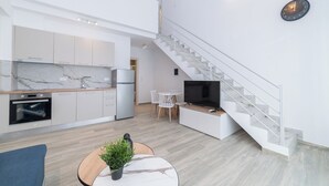 Un apartamento moderno con cocina, comedor y escalera.
