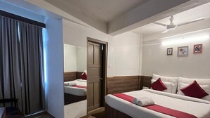 Ein Hotelzimmer mit Bett, Schreibtisch, Stuhl, Tür und Deckenventilator.
