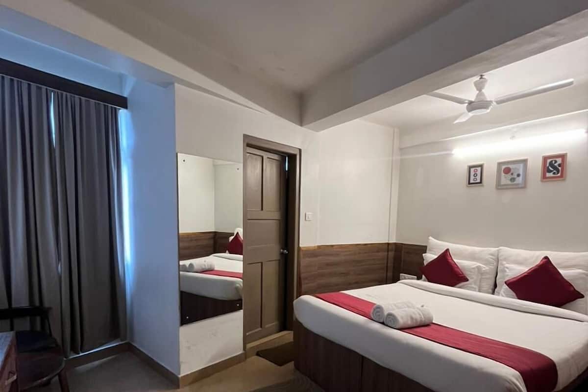A hotel room with a bed, a desk, a chair, a door, and a ceiling fan.