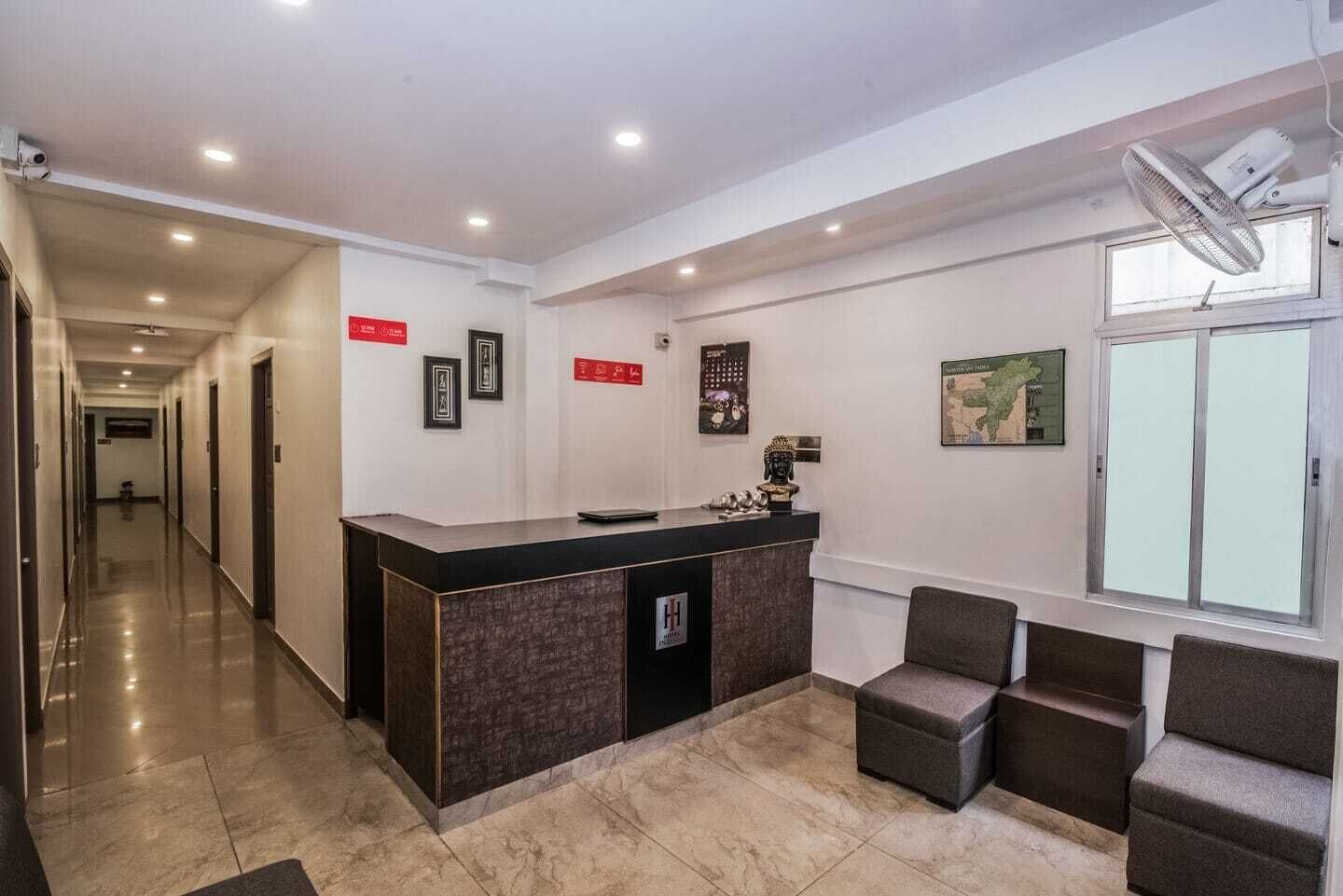 A hotel reception area with a reception desk, seating area, and a hallway leading to other rooms.
