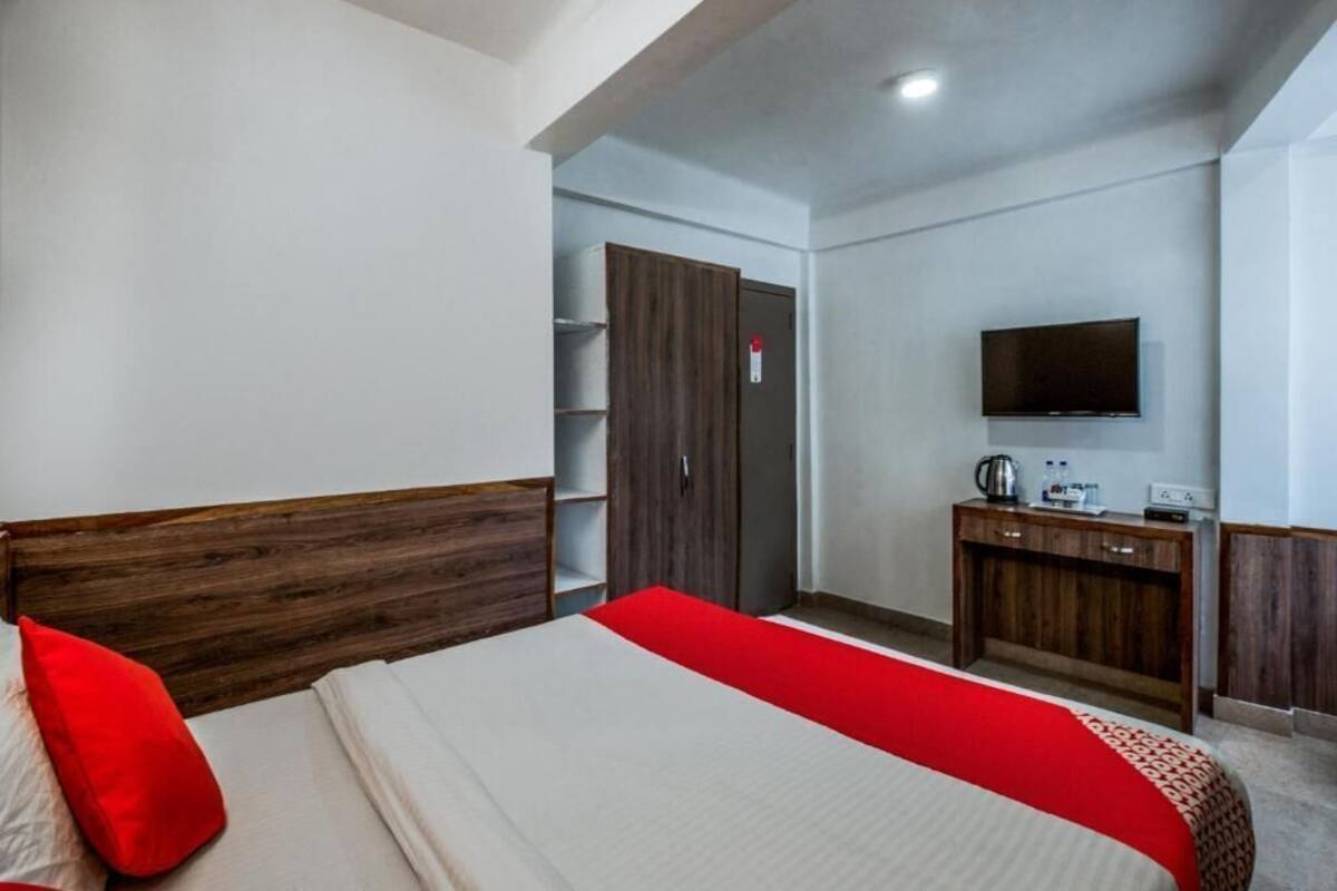 A bedroom with a bed, a TV, a wardrobe, and a desk with a kettle.