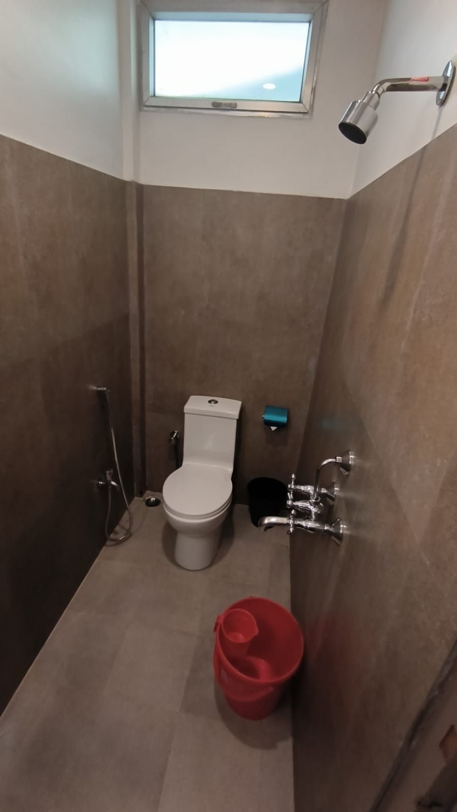 Un baño pequeño con inodoro, ducha y ventana.