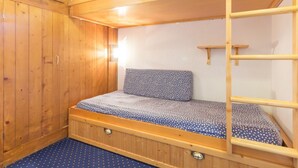 A bunk bed room with wooden walls and a blue polka dot bedspread. - Cozy ski-in studio with balcony (Les Arcs 1800)