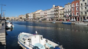 A waterfront with boats docked along the shore, buildings with balconies, and a clear blue sky. - 1-bedroom apartment with garage and pool in Sète (Sète)