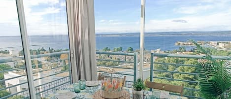 Un balcón con una mesa lista para comer, con vistas a la ciudad y al mar.