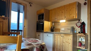 Cocina compacta con armarios de madera, microondas, horno y cafetera.