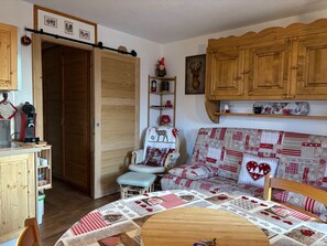 Ein gemütliches Wohnzimmer mit einer Holzdinette, einem Esstisch mit einer Decke und einer Küchenzeile mit Holdekor und einer Kaffeemaschine.