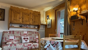 Una habitación acogedora con un sofá de madera, una mesa de comedor y un aparador de madera.