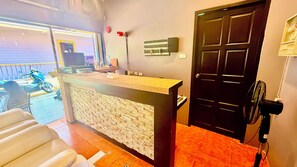 Un mostrador de recepción con fachada de piedra, una puerta negra y un ventilador.