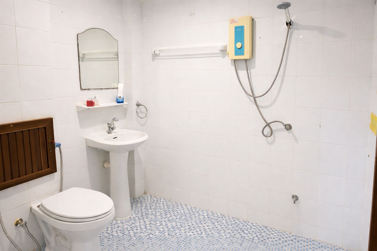 A small bathroom with a toilet, sink, and shower.