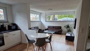 Ein kompakter Wohnraum mit Küchenzeile, Essbereich und Sitzgelegenheit.