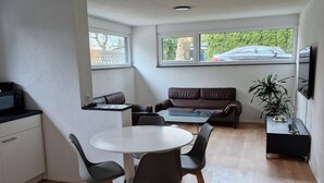 Eine moderne Küche mit Essbereich, einer Couch und einem an der Wand befestigten Fernseher.
