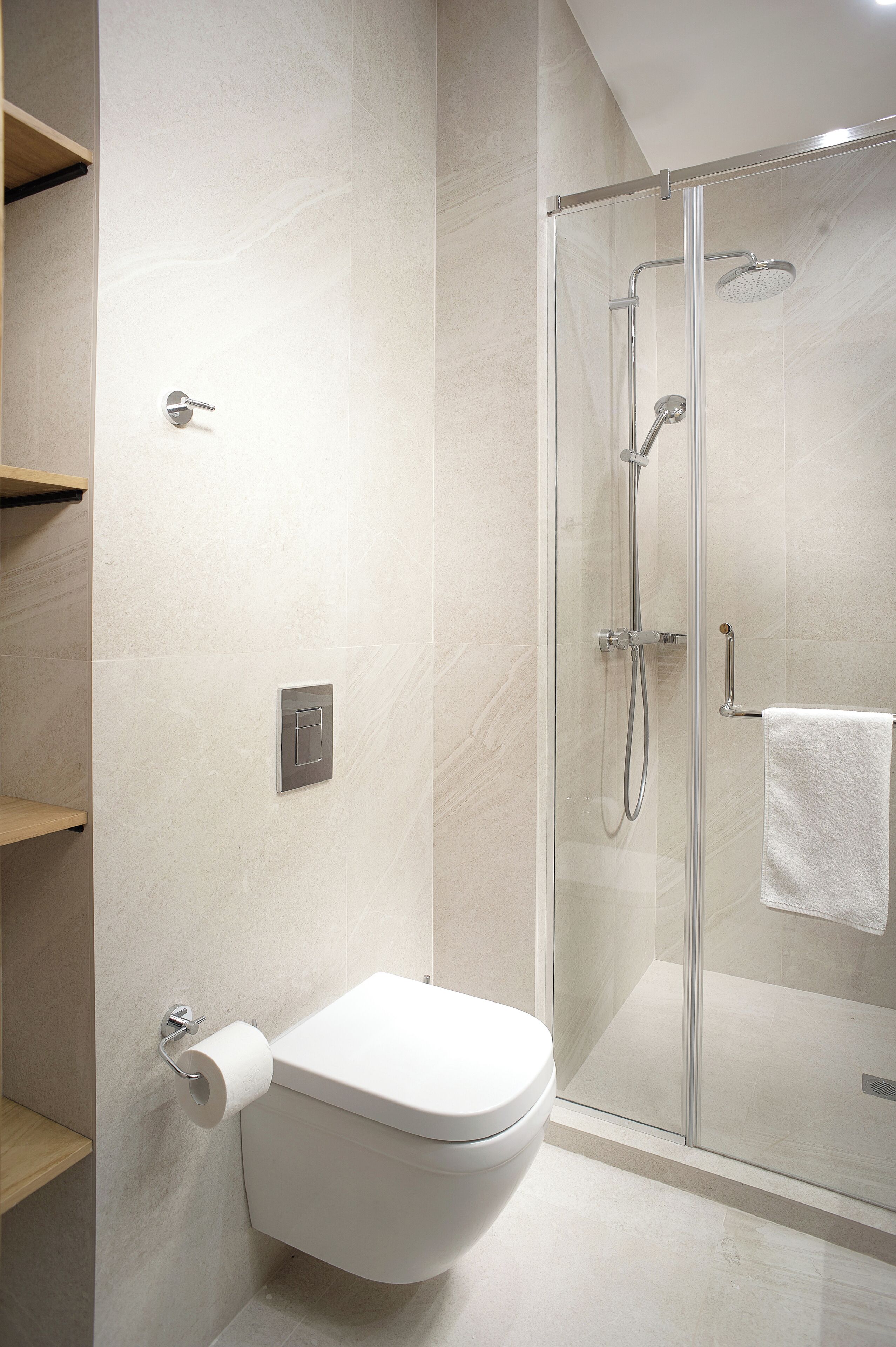 Un baño moderno con inodoro, ducha con mampara de vidrio y barra para toallas.