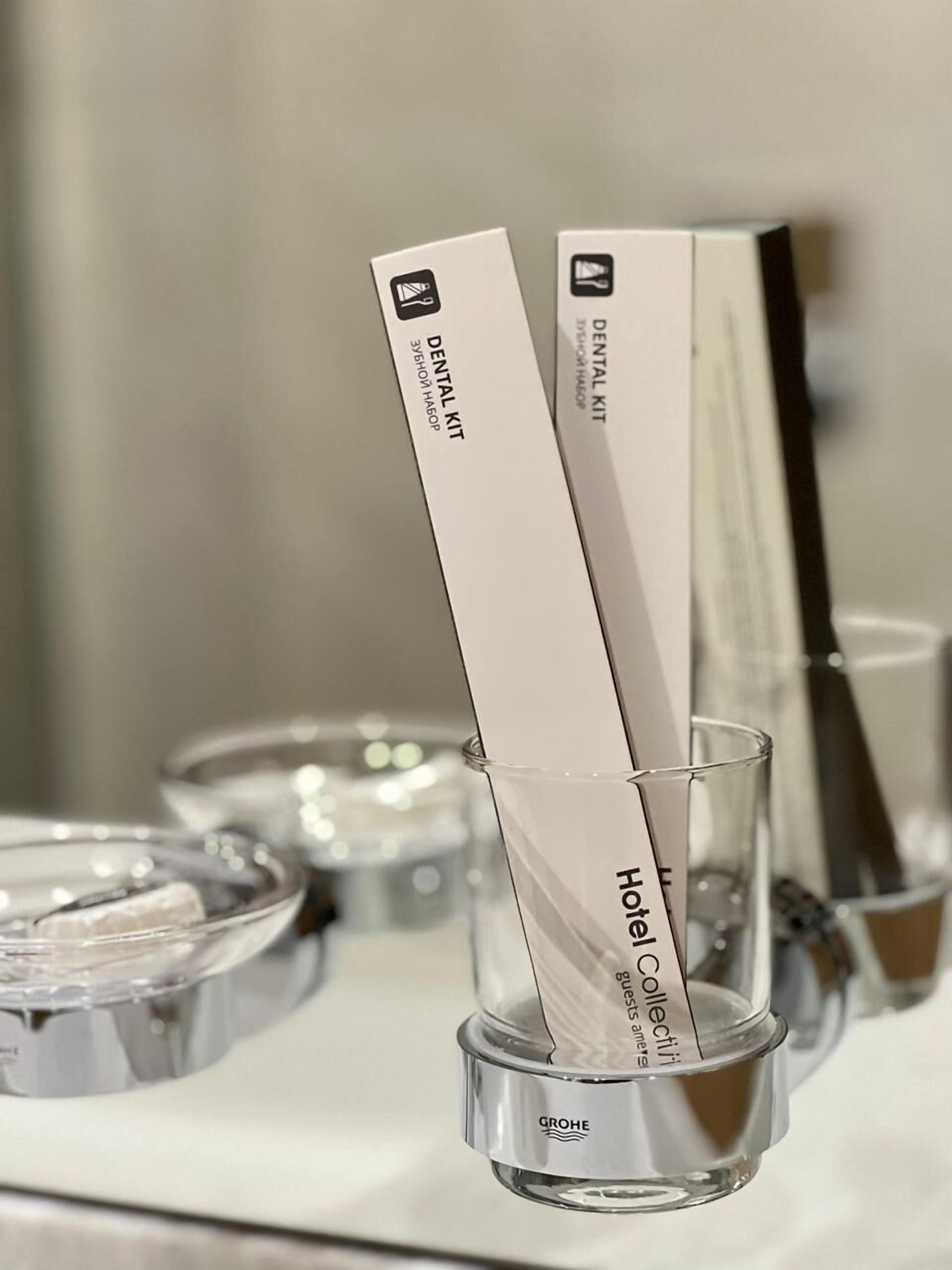 A glass with a white label reading "Hotel Collection" and a box labeled "Dental Kit."