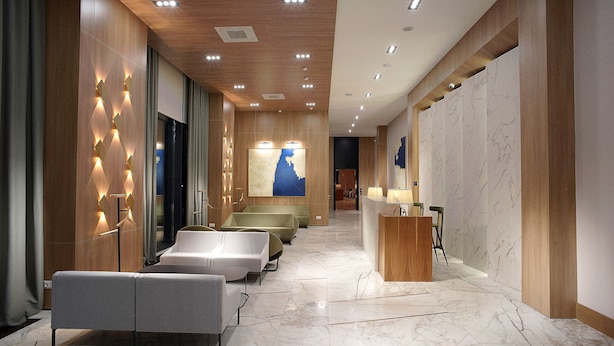 Eine moderne Hotellobby mit einer Rezeption, einer Sitzecke und einem großen Wandbild.