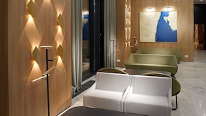 Eine moderne Hotellobby mit Holzvertäfelung, einem großen abstrakten Gemälde und Sitzbereichen.