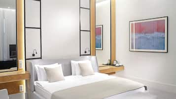 A modern bedroom with a bed, bedside tables, a bench, a TV, and artwork on the walls.
