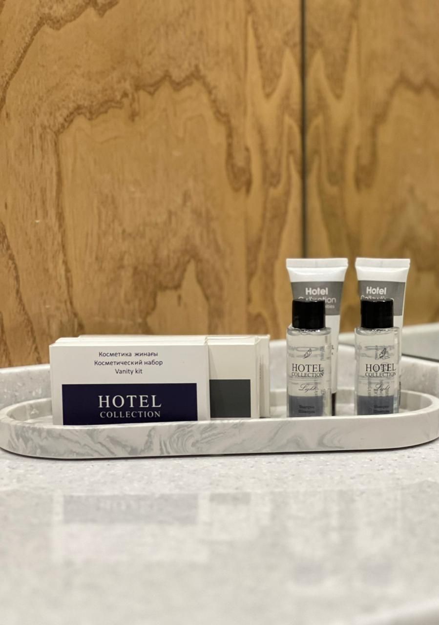 A tray with a vanity kit and two Hotel Collection bottles.
