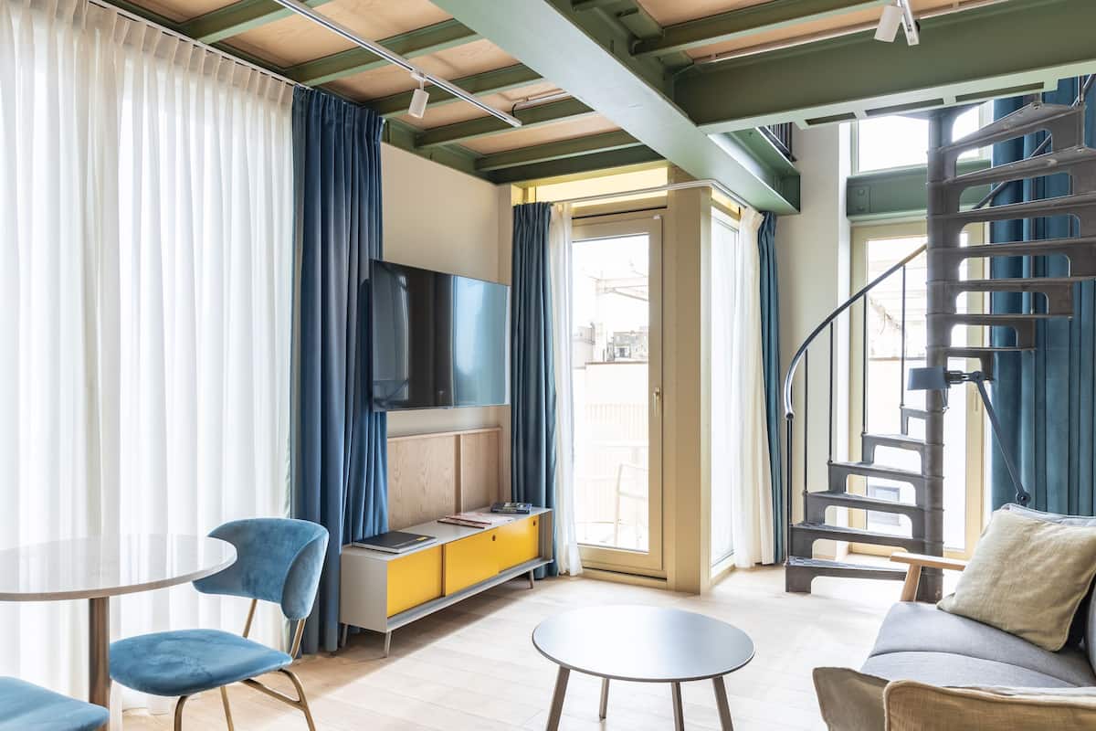 Un salon moderne comprenant un canapé, deux fauteuils, une petite table, un téléviseur et un escalier.