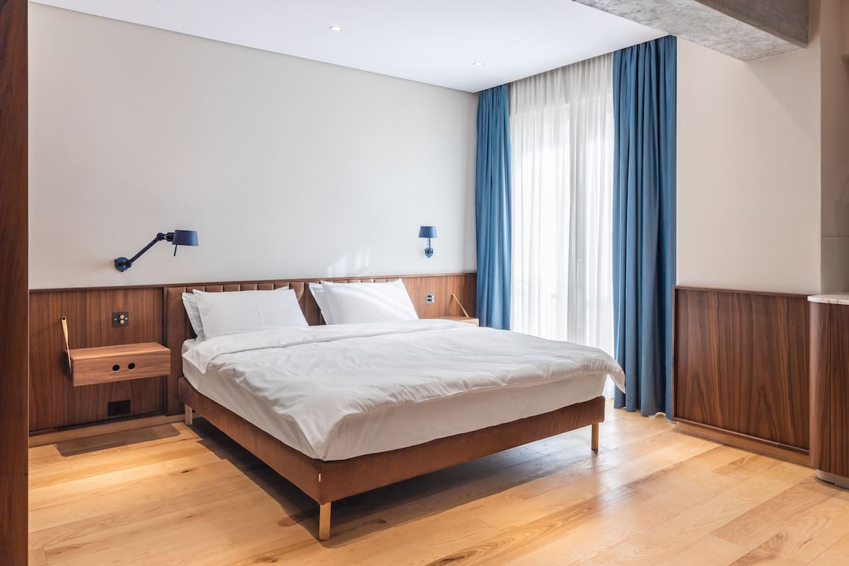 Une chambre à coucher moderne avec un lit en bois, des tables de chevet et une petite table de nuit.