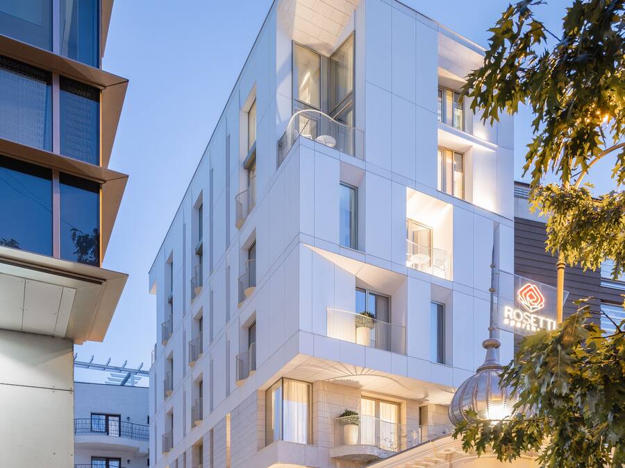 Un hotel de varios pisos con un diseño moderno, que cuenta con balcones y una escalera que conduce a la entrada.
