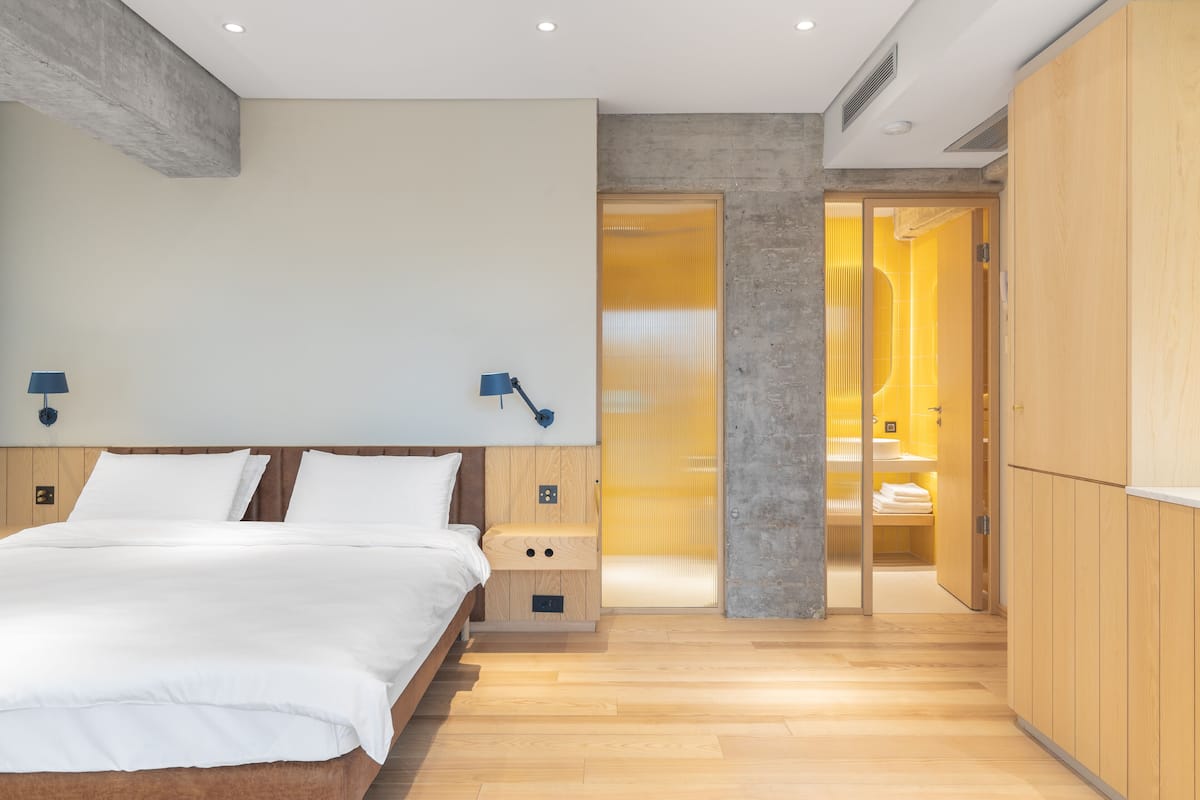 Une chambre à coucher moderne avec un lit en bois, des lampes de chevet et un dressing doté d’un miroir.