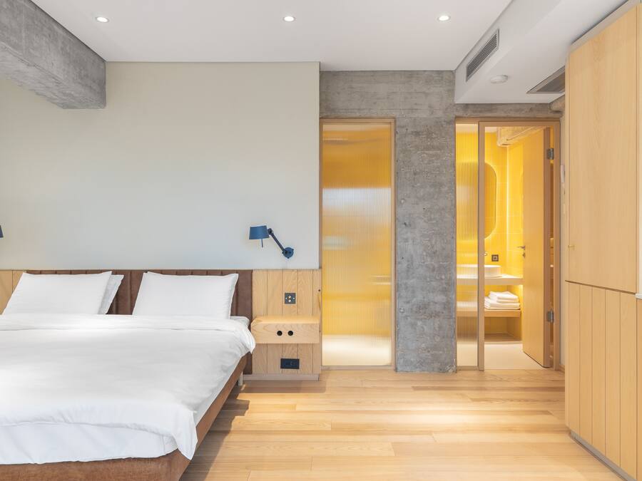 Un dormitorio moderno con una cama de madera, lámparas de noche y un vestidor con espejo.