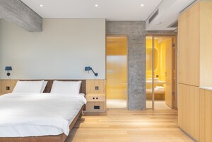 Un dormitorio moderno con una cama de madera, lámparas de noche y un vestidor con espejo.