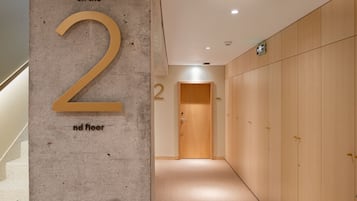 A hallway with a large number '2' indicating the 2nd floor, wooden lockers, and a door at the end.
