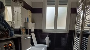 A compact bathroom with a washing machine, a toilet, and a sink. - Wake'nBake Affittacamere (Genoa)