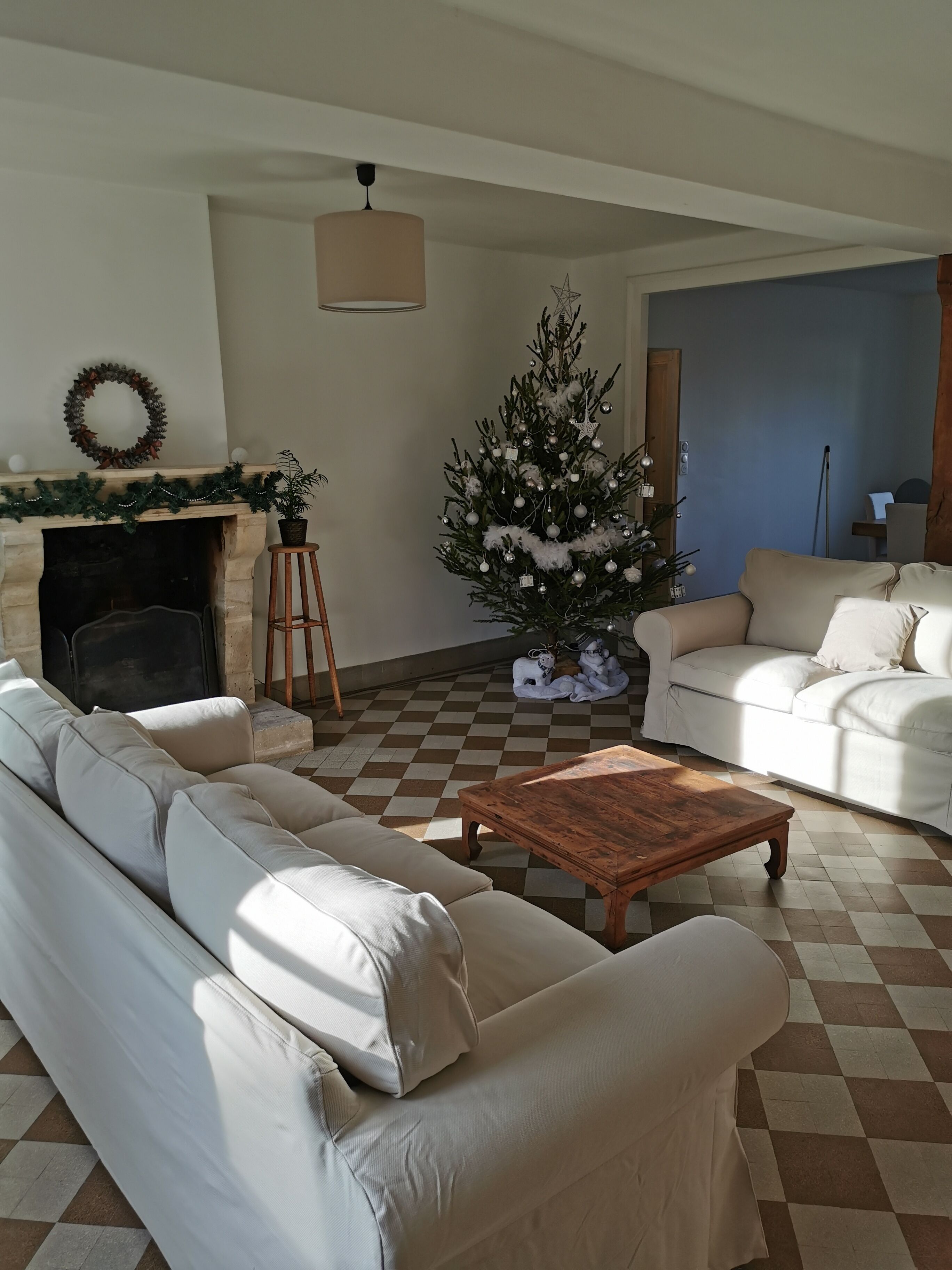 Ein Wohnzimmer mit Kamin, Weihnachtsbaum, einer Couch und einem Couchtisch.