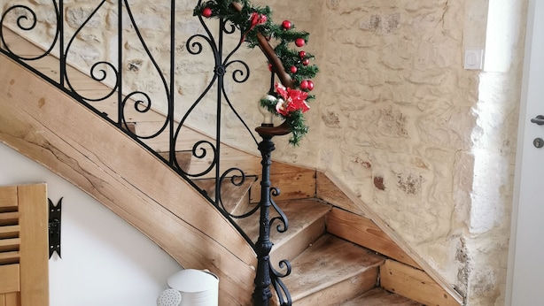 A staircase with a wrought iron railing, decorated with greenery and red ornaments. - Gîte des frangines (Beaumont)