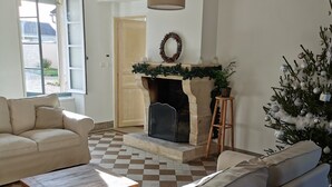A living room with a fireplace, a sofa, a coffee table, and a Christmas tree. - Gîte des frangines (Beaumont)