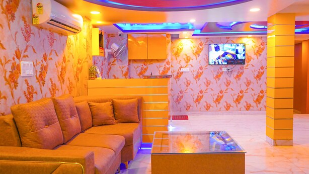 A modern living room with a sofa, a glass coffee table, and a flat-screen TV mounted on the wall.