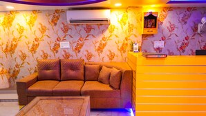 A reception area with a sofa, a glass-top table, and a bright orange counter.