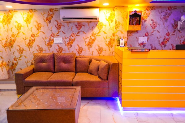 A reception area with a sofa, a glass-top table, and a bright orange counter.