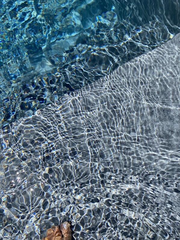 A clear pool with visible ripples and a person's foot at the bottom.