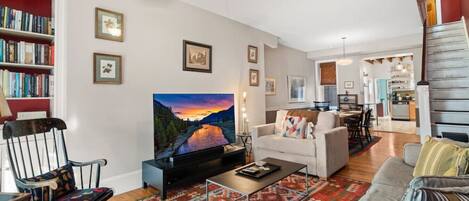 Una sala de estar con televisor, sofá, mesa de centro y alfombra estampada.