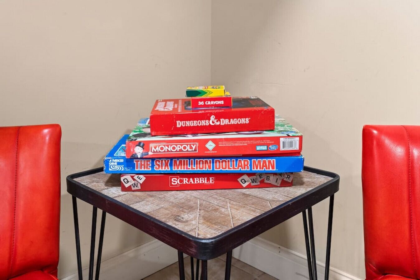 Une table sur laquelle est posée une pile de jeux de société, notamment le Monopoly, le Scrabble et d’autres jeux.