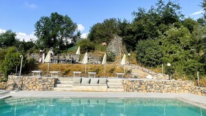 A swimming pool with lounge chairs and umbrellas, surrounded by stone steps and greenery. - #1 Cinque Terre, Tuscany, Liguria, Lerici (Liguria)