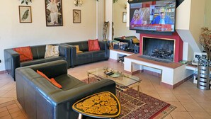 A living room with a sofa, a coffee table, a fireplace, and a television. - Stylish Villa (6 or 8 bedrooms) with Private Pool, 40 minutes from Florence (Pistoia)