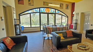 A living room with two sofas, a coffee table, and a dining area with chairs and a table. - Stylish Villa (6 or 8 bedrooms) with Private Pool, 40 minutes from Florence (Pistoia)