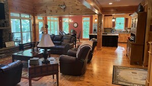 A spacious living room with a fireplace, leather sofas, and a dining area. - Beautiful Lakefront Retreat  (Eatonton)