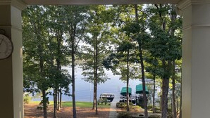 A porch with a view of a lake, trees, and boats. - Beautiful Lakefront Retreat  (Eatonton)