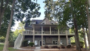 A two-story house with a front porch, a covered front entrance, and a staircase leading to the upper level. - Beautiful Lakefront Retreat  (Eatonton)