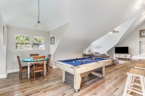 A spacious room with a pool table, a sofa, and a television.