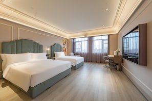 Une chambre d’hôtel avec deux lits, un bureau et une télévision.