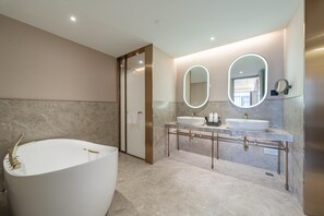 Une salle de bain moderne avec une baignoire sur pieds, deux vasques et un grand miroir.
