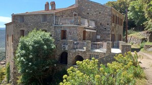 A stone building with a balcony, arched windows, and a view of the surrounding landscape.