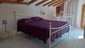 Une chambre à coucher avec un lit, une table de chevet, une lampe et une fenêtre avec des rideaux.